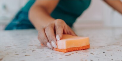Mano limpiando la mesa de una cocina con Esponja Cero Rayas Scoth-Brite.
