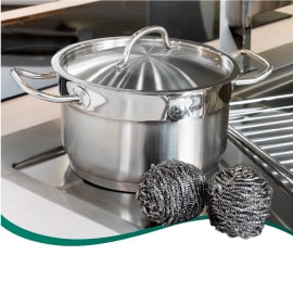 Olla de aluminio y espiral metálico Scotch-Brite sobre la superficie de un lavabo.