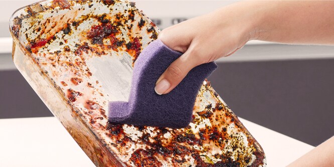 Mano lavando un refractario con la Fibra Esponja Extrema Scoth-Brite.
