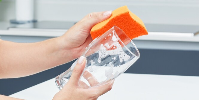 Mano lavando copa de cristal con jabón y Fibra Esponja Cero Rayas Scoth-Brite.
